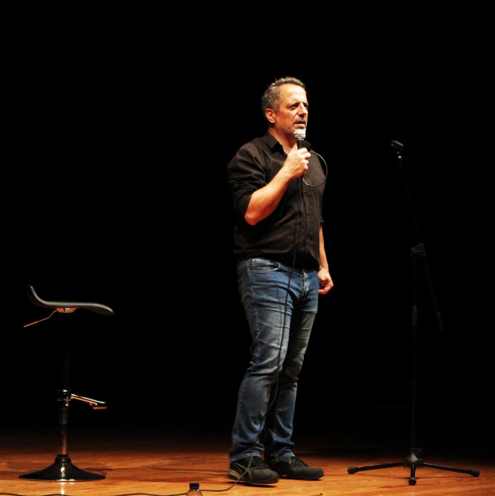 João Seabra sozinho em palco num auditório